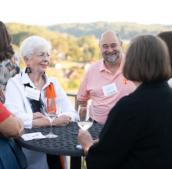 A group of UT Health Science Center alumni in conversation around a table.